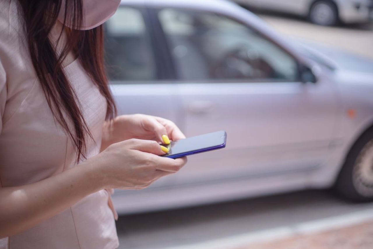 Person on phone next to car - How long does a car insurance claim take?